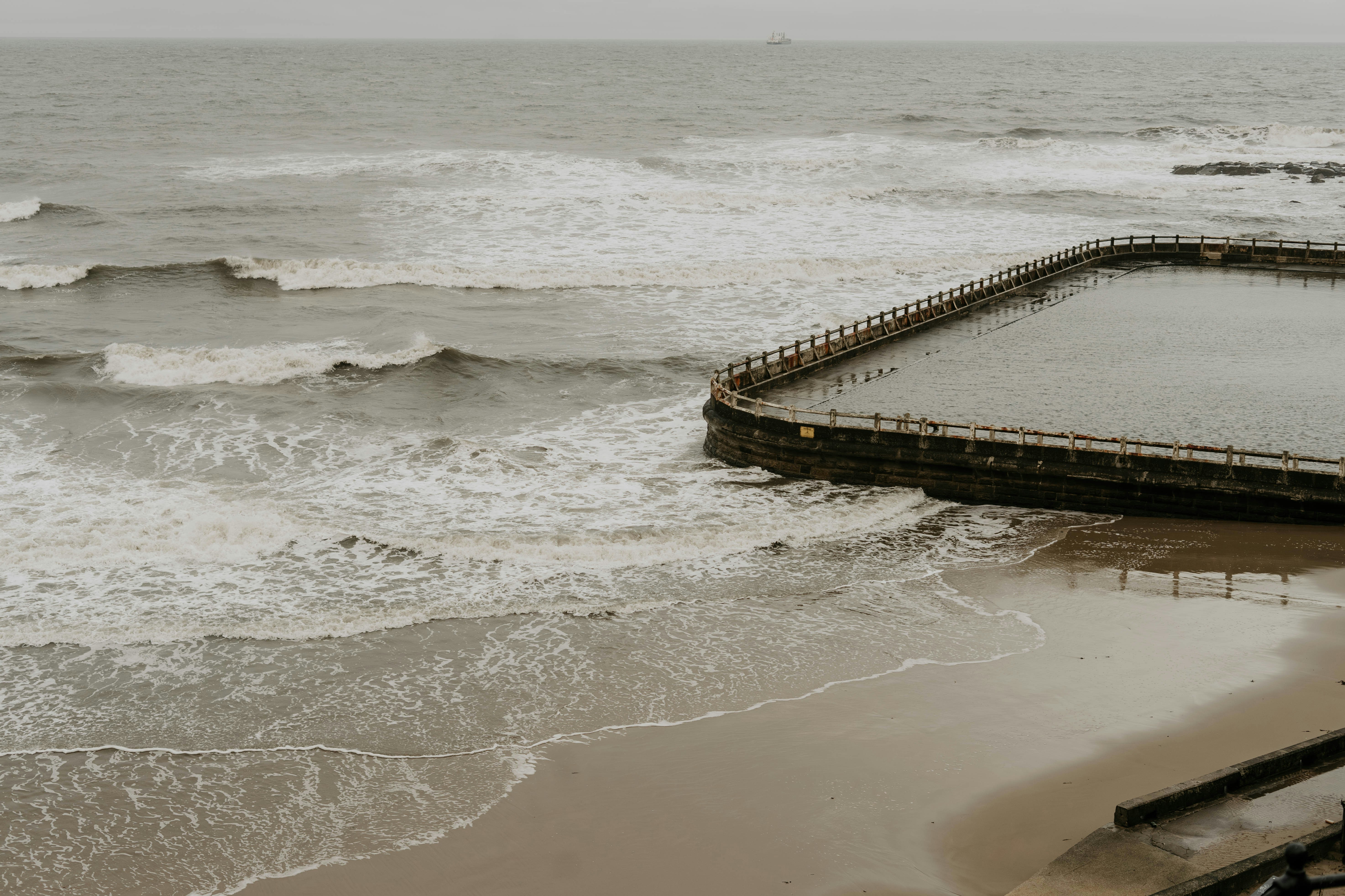 a pier on a beach next to the ocean