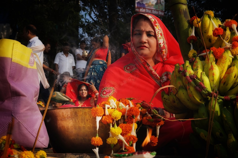 a woman in a red sari sitting next to a bunch of bananas