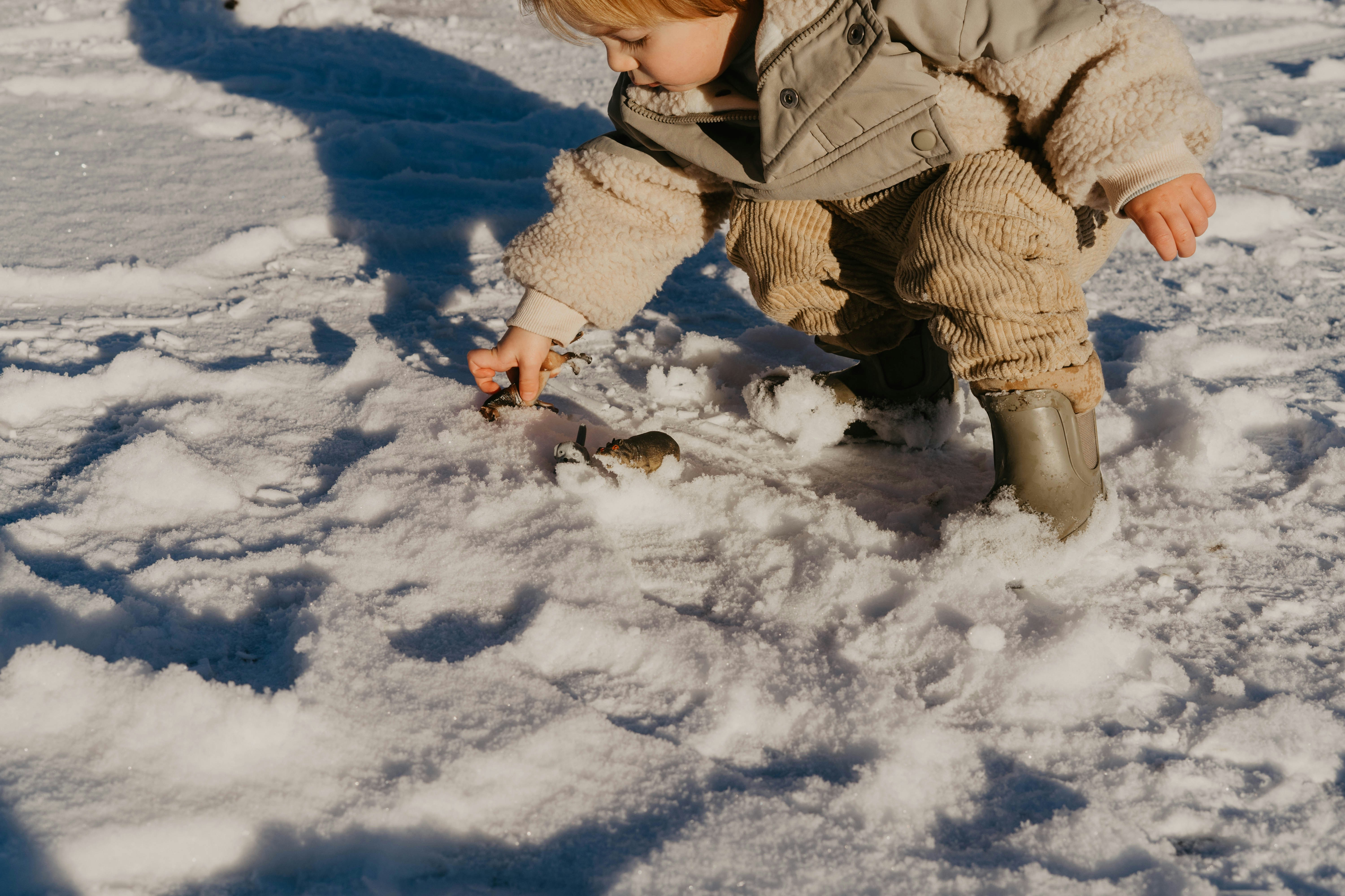 a little boy playing in the snow with a bird