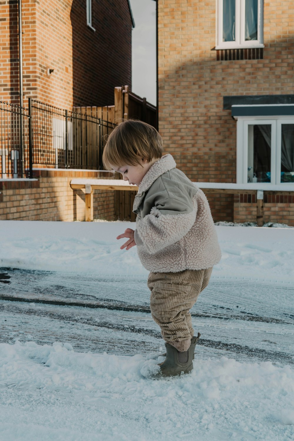 a little boy playing in the snow in front of a house