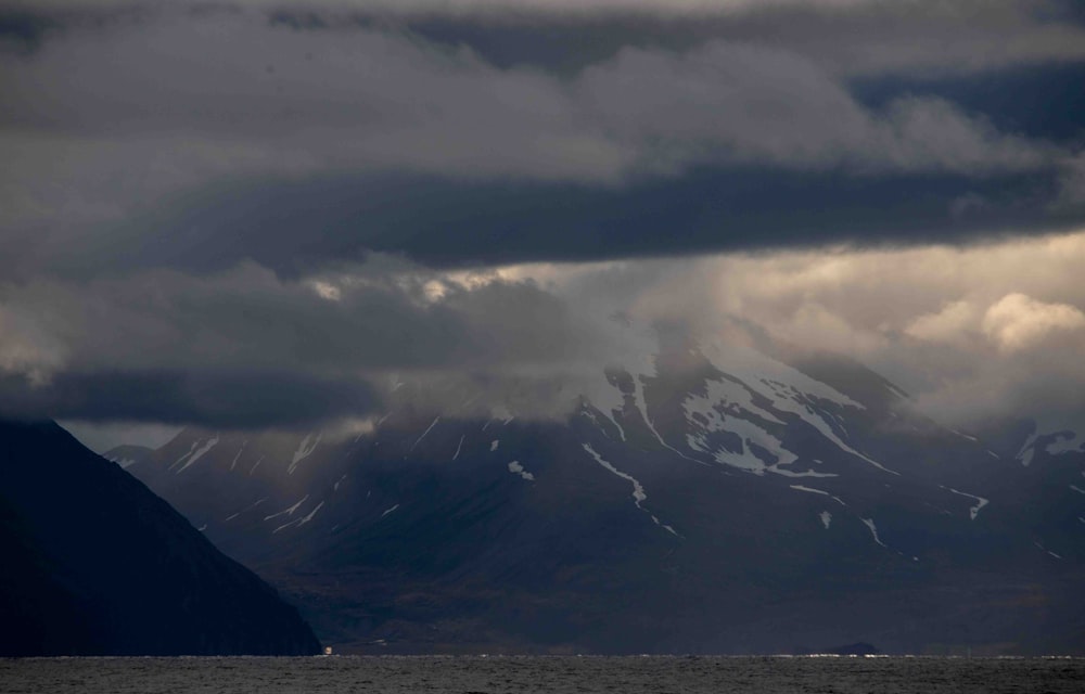 a large mountain covered in snow under a cloudy sky