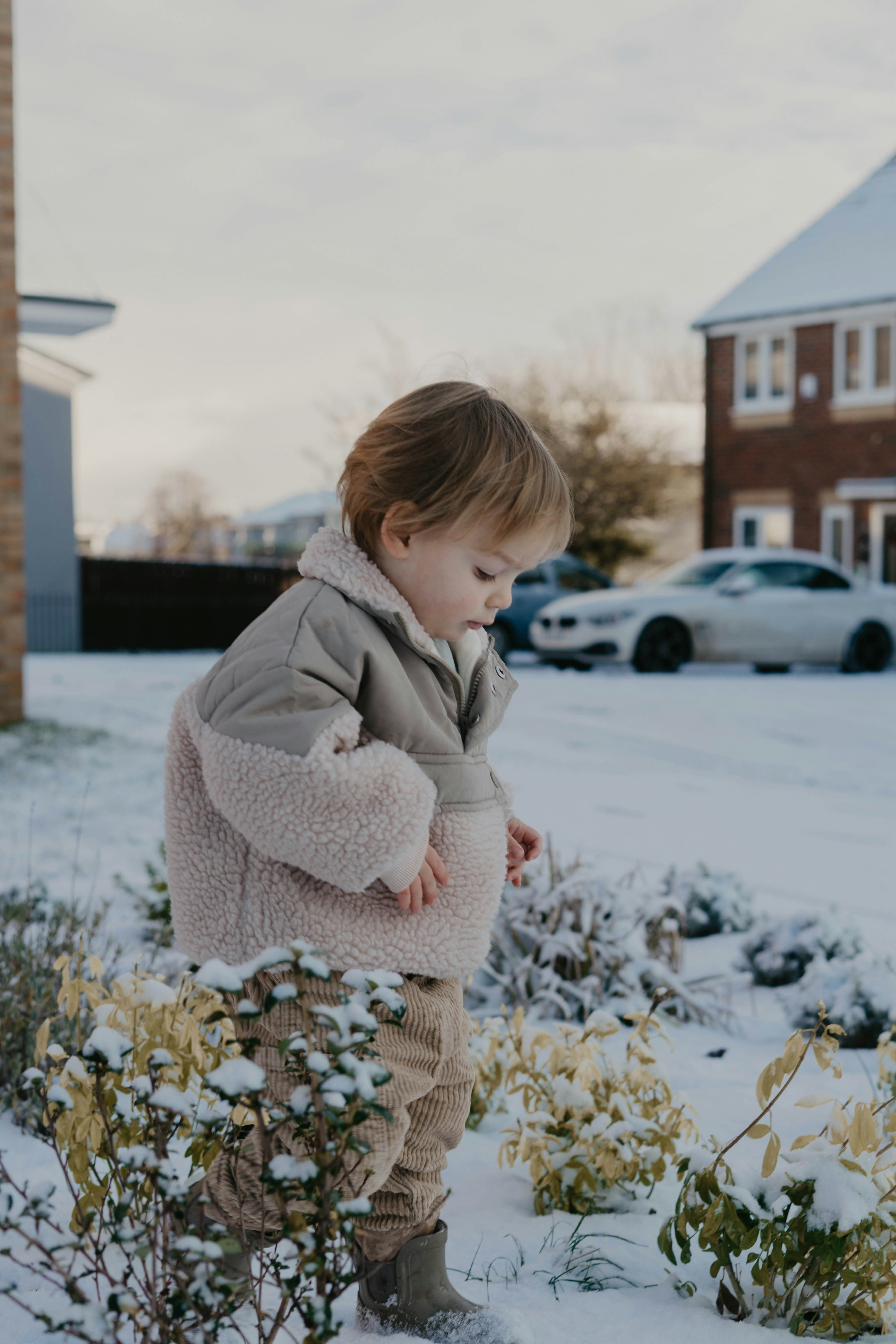 a little girl standing in the snow with a jacket on