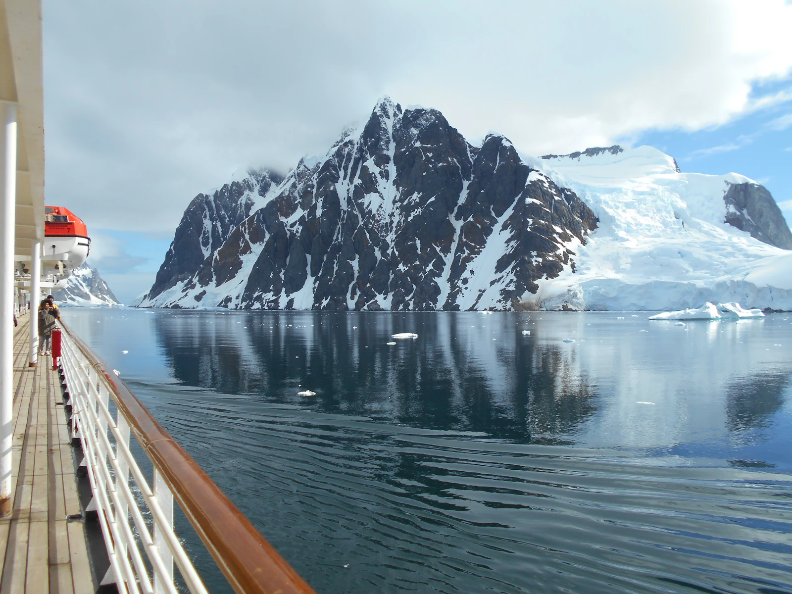 An expedition ship gliding past the Antarctic peaks
