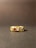 A gold ring adorned with multiple gemstones sits on a flat surface. The stones come in various shapes and colors, including red, blue, green, and clear, set within the band
