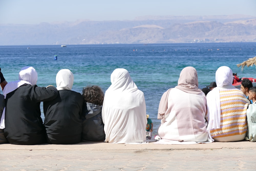 a group of people sitting on top of a sandy beach