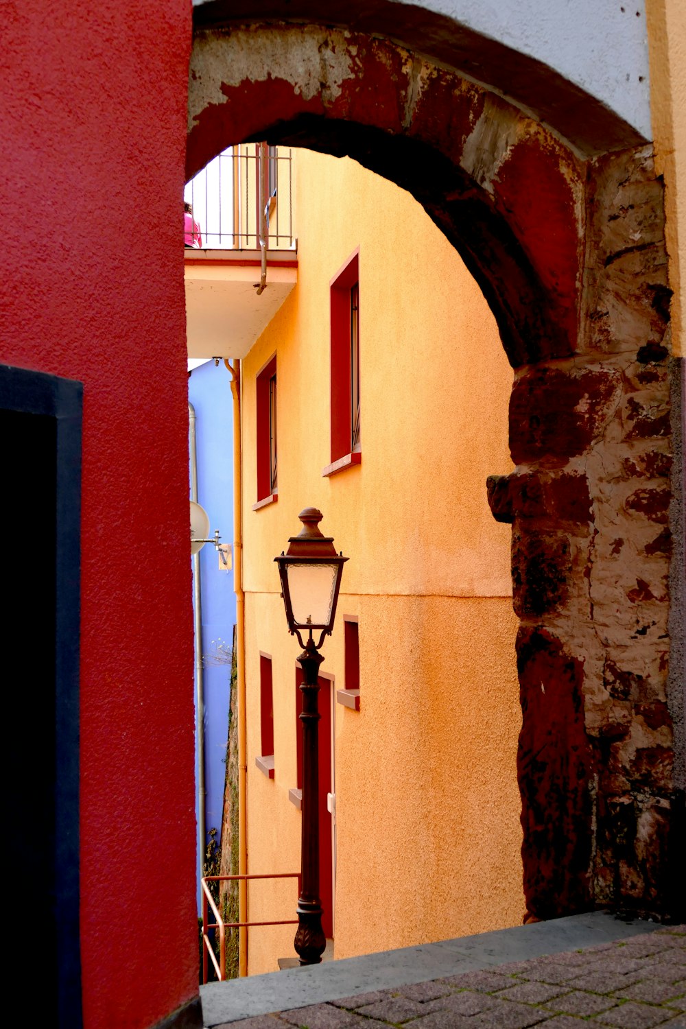 a narrow alley way with a lamp post and a red building