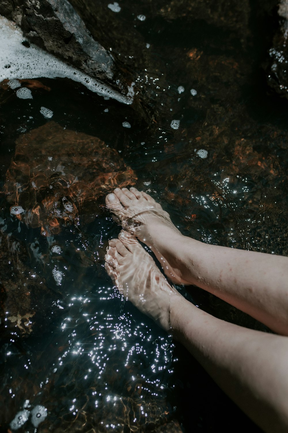 a person's bare feet in a stream of water