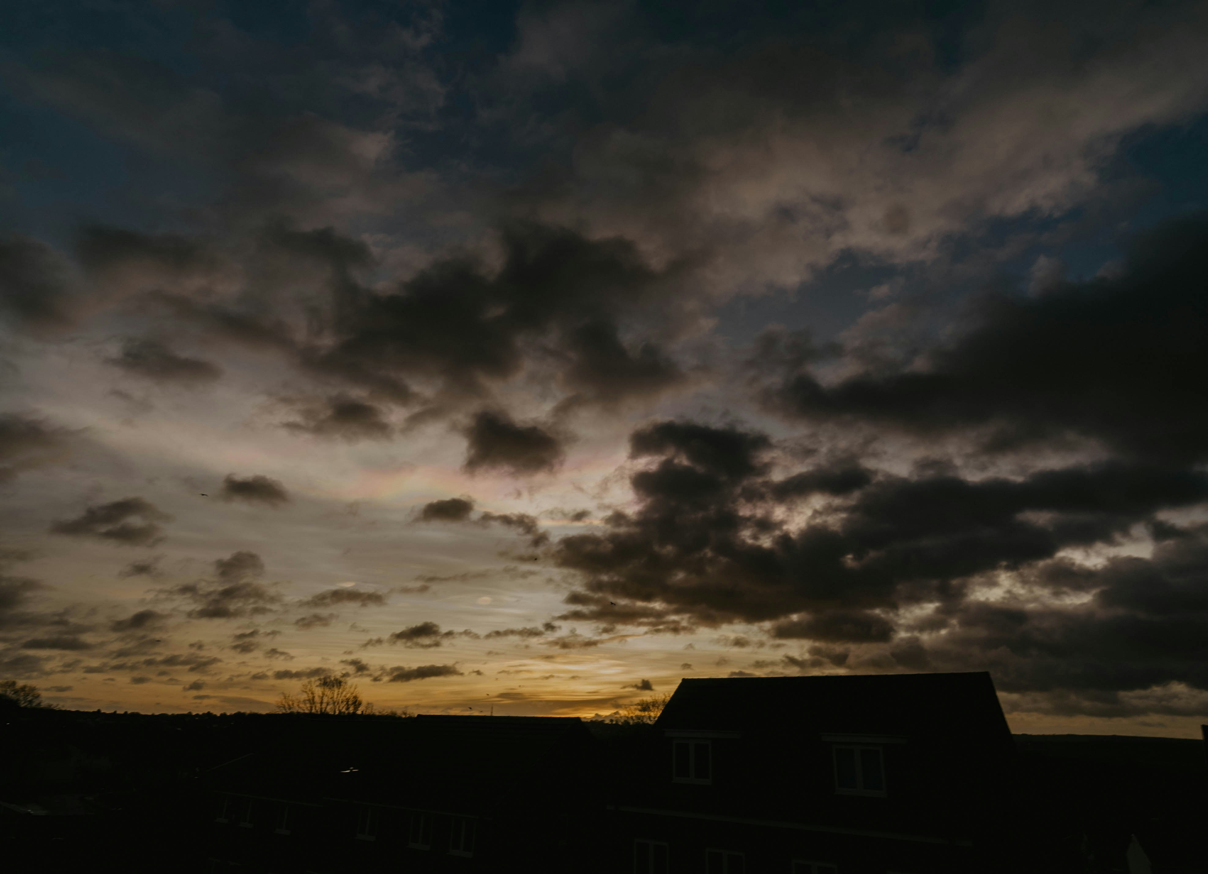 a dark sky with clouds and a building in the foreground
