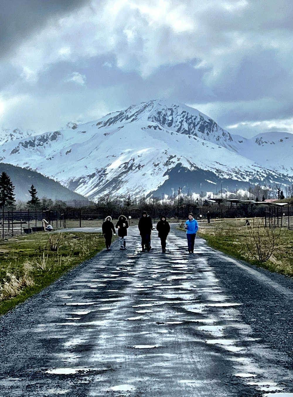 a group of people walking down a road with a mountain in the background