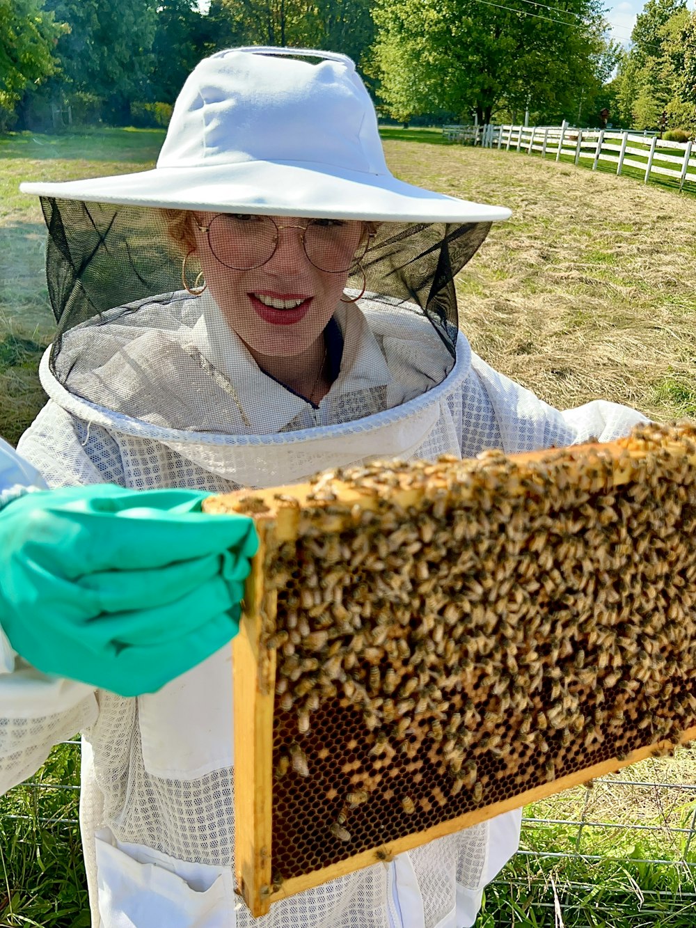 a woman in a bee suit holding a beehive