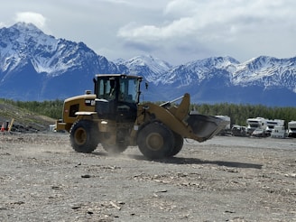 a bulldozer moving dirt in front of a mountain range