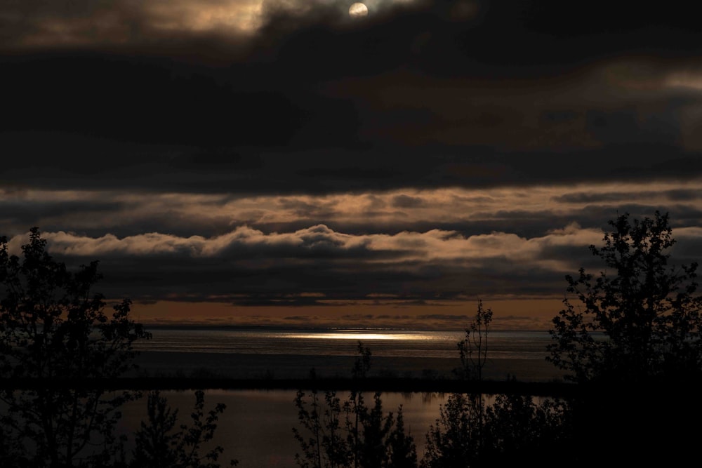 a full moon shines through the clouds over a body of water