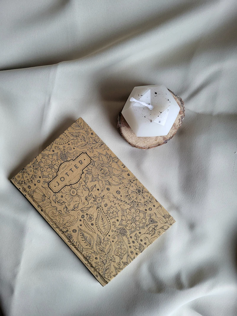 Candle beside a book on white bedding