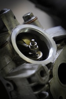 A close-up view of an engine component, showcasing detailed metal parts with a focus on a circular opening and a visible bolt in the center.