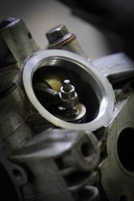 A close-up view of an engine component, showcasing detailed metal parts with a focus on a circular opening and a visible bolt in the center.