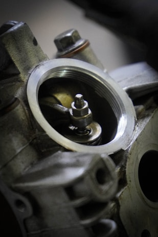 A close-up view of an engine component, showcasing detailed metal parts with a focus on a circular opening and a visible bolt in the center.