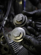a close up of a person wearing black gloves holding a metal object