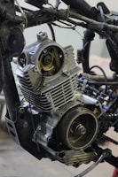A detailed view of a partially disassembled motorcycle engine is surrounded by various metal parts and wires.