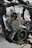 A detailed view of a partially disassembled motorcycle engine is surrounded by various metal parts and wires.