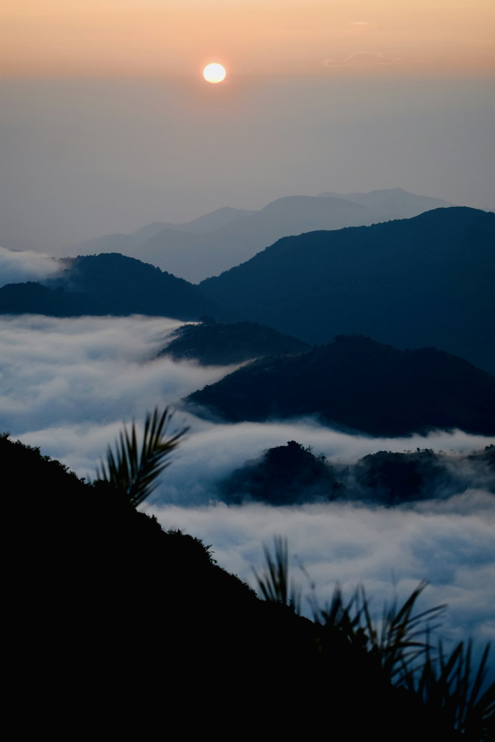 the sun is setting over the clouds in the mountains