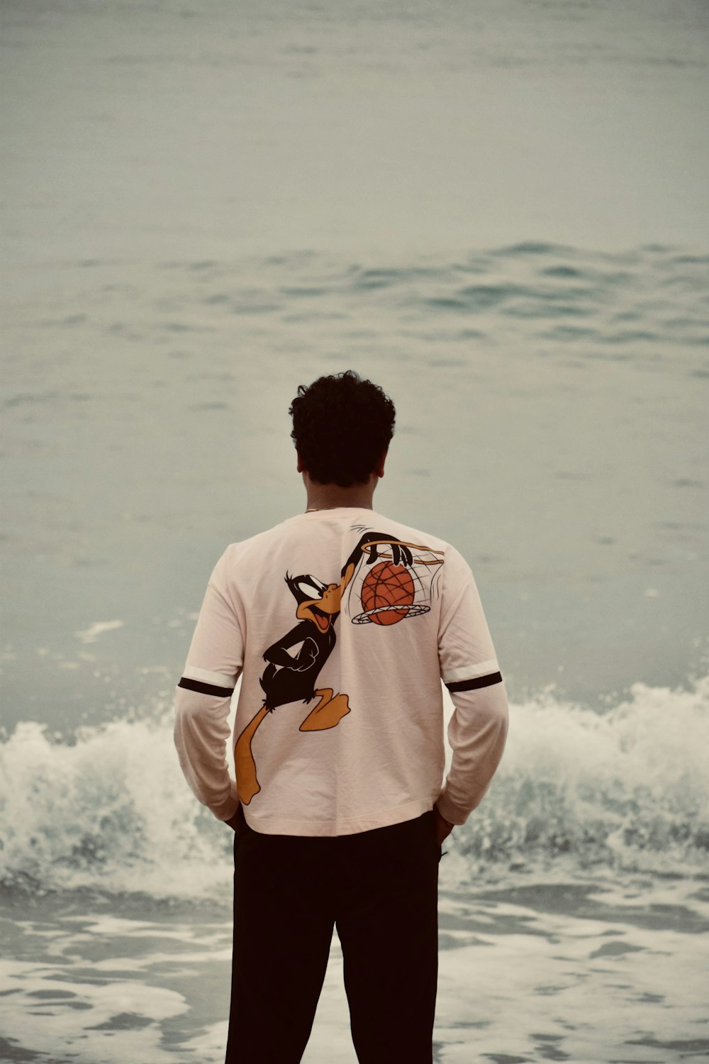 a man standing on top of a beach next to the ocean