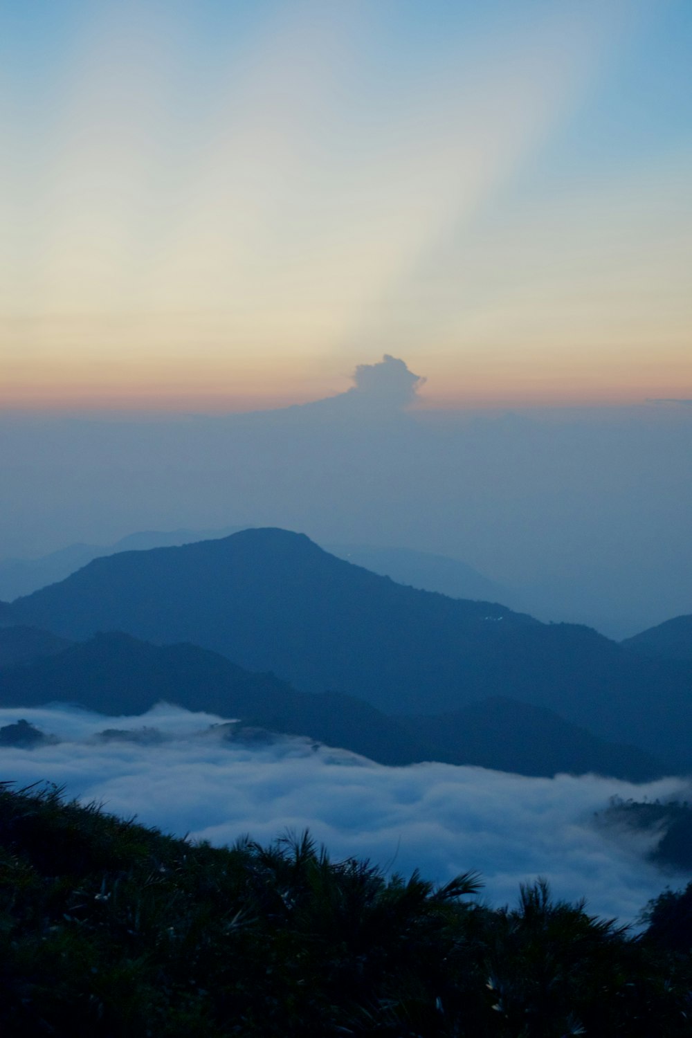 the sun is setting over the mountains and clouds