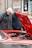 two men looking under the hood of a red car