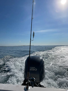 A sleek fiberglass fishing boat cutting through deep blue ocean waters under a clear sky.