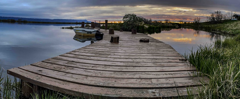 a wooden dock sitting on top of a lake under a cloudy sky