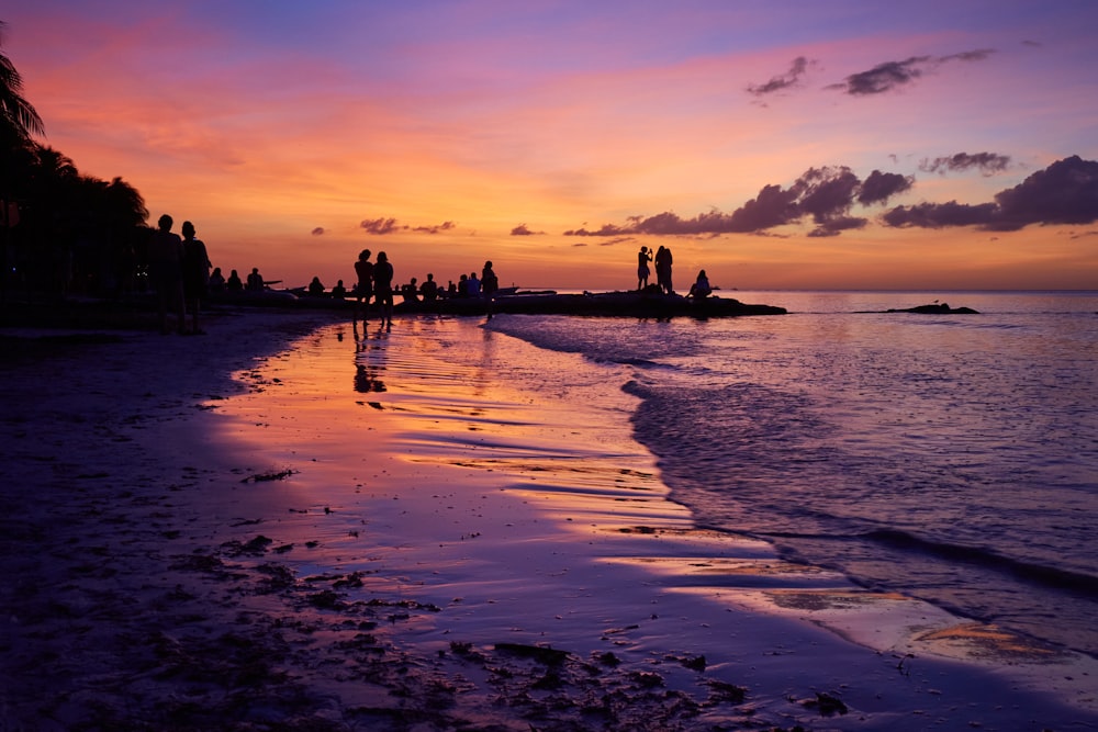 uma praia ao pôr do sol com pessoas caminhando sobre ela