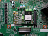 A printed circuit board with various electronic components and integrated circuits, prominently featuring a large black chip labeled 'PHOENIX ICU PRG 0770Z1-1'. Several capacitors are visible, along with numerous small resistors and connectors. There is a green LED light illuminated on the board, and the surface is covered with intricate traces and solder points.