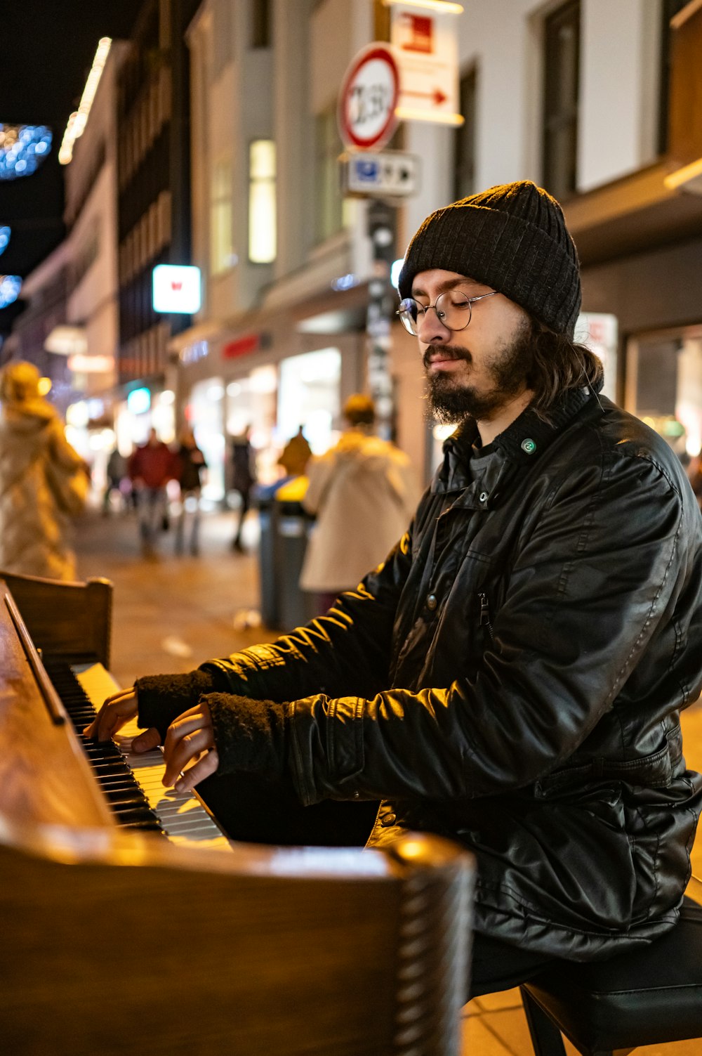 a man sitting at a piano on a city street
