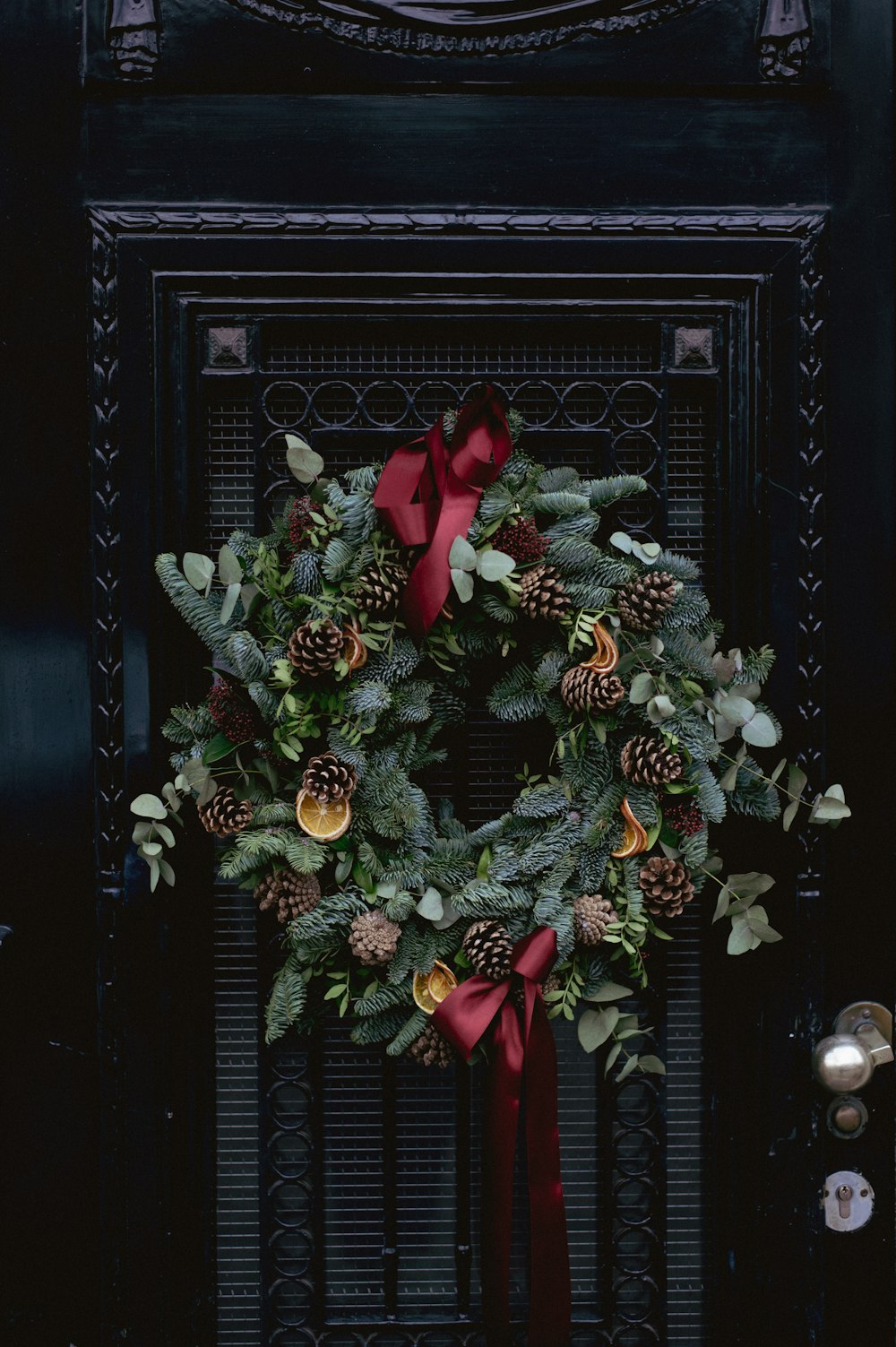 a christmas wreath on a door with a red bow