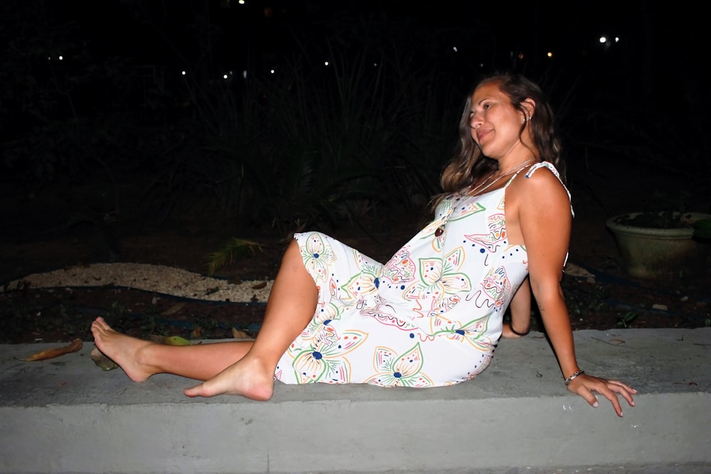 a woman is sitting on a ledge at night