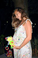 A mother-to-be opening gifts surrounded by smiling friends and family.