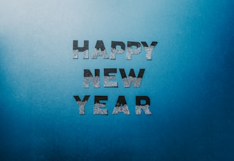 Silver glitter text of 'Happy New Year' is set against a gradient blue background.