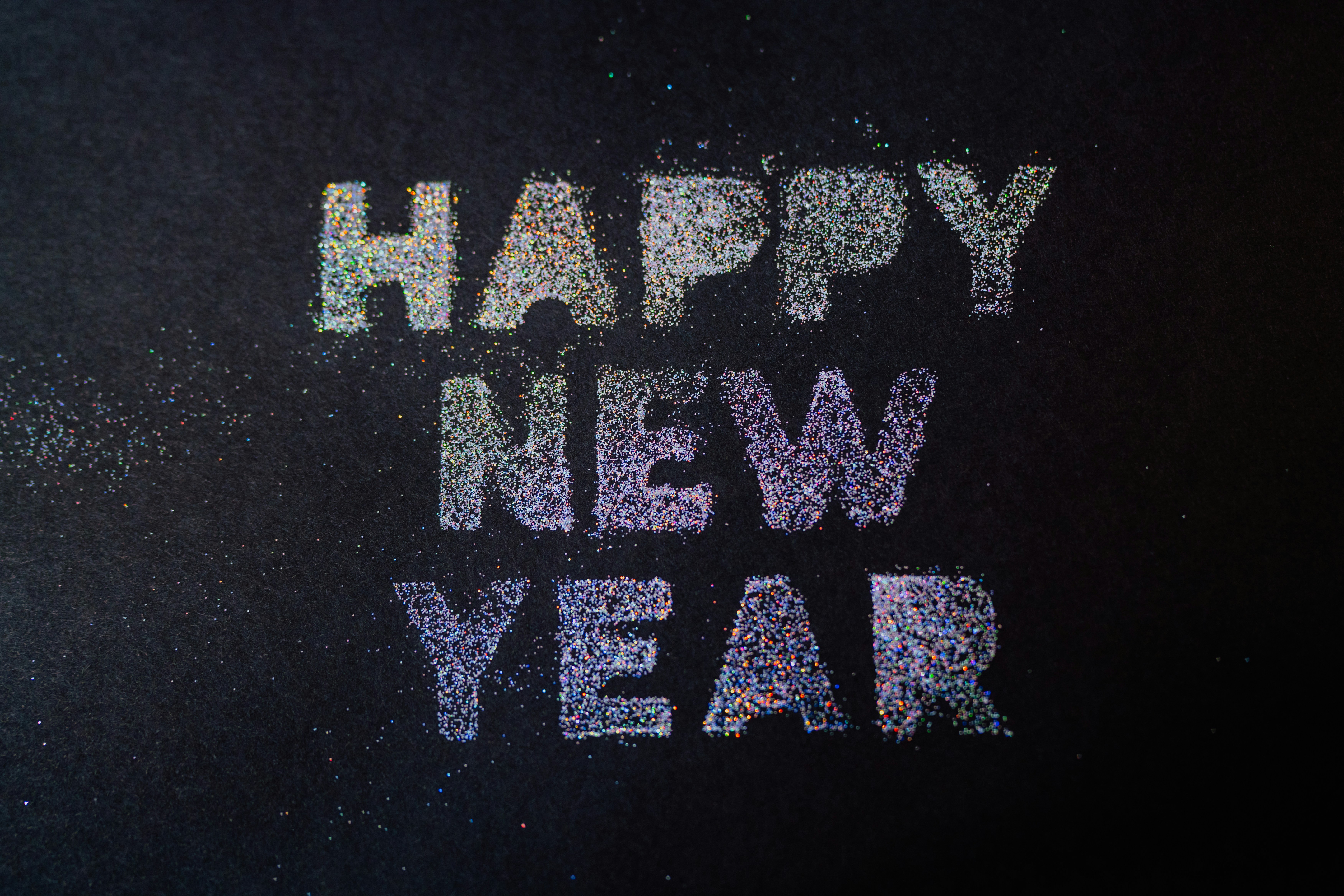 The words "Happy New Year" spelled out in glitter on a dark background.