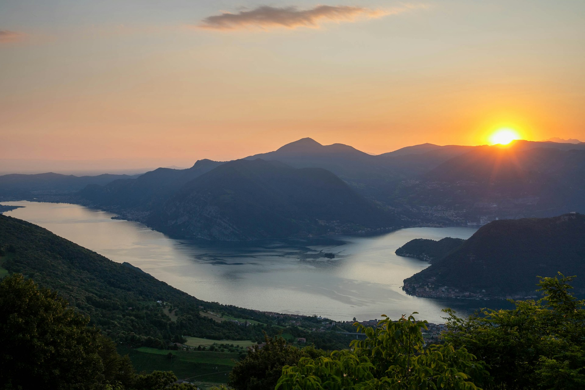 A beautiful landscape photograph showcasing a serene lake surrounded by mountains during sunset.
