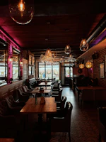Cozy interior shot highlighting warm wooden tables and filament bulb lighting.