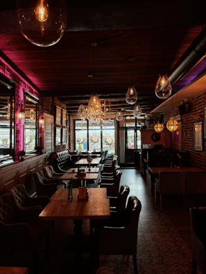 Cozy interior shot highlighting warm wooden tables and filament bulb lighting.