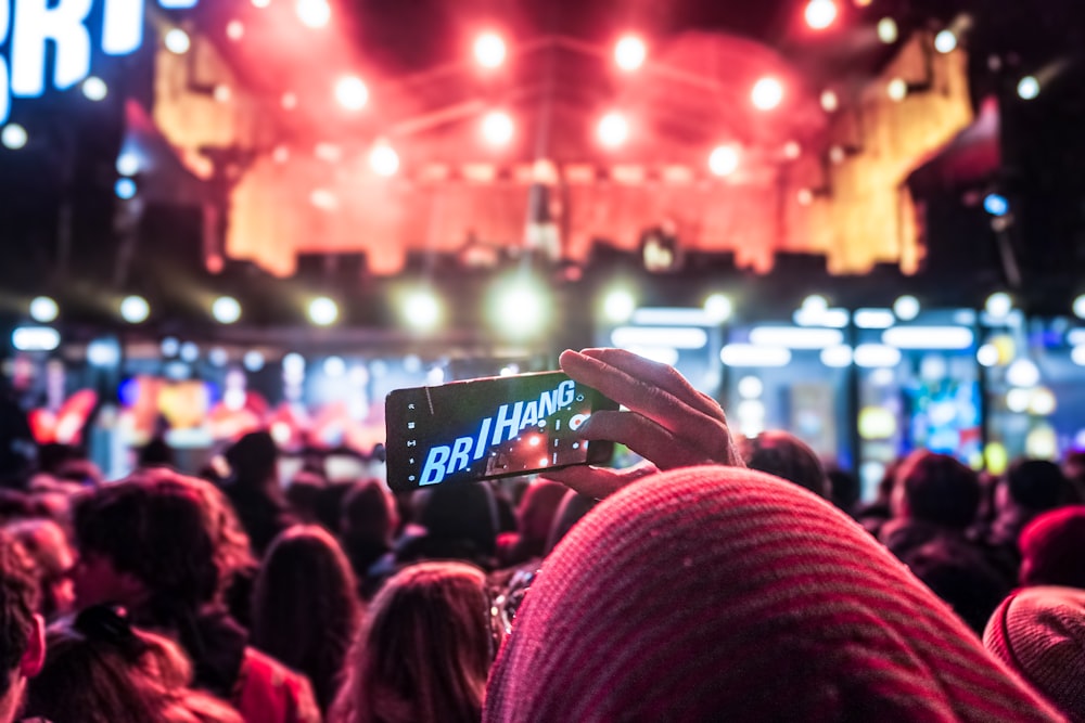 a person holding up a cell phone in front of a crowd