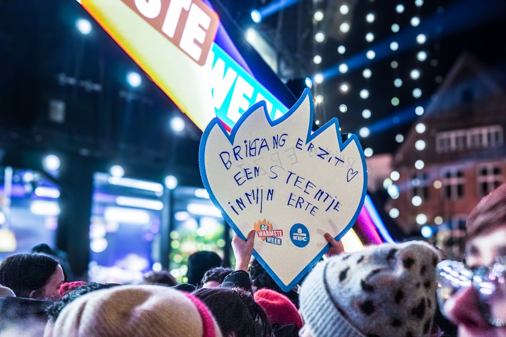 a person holding a sign in the middle of a crowd