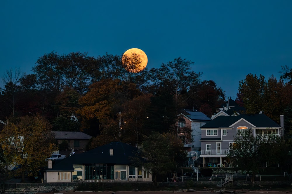 a full moon is seen over a row of houses