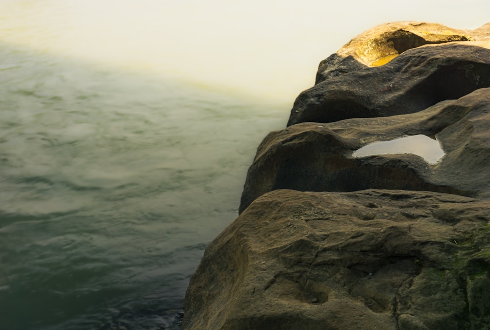 a large rock sticking out of a body of water