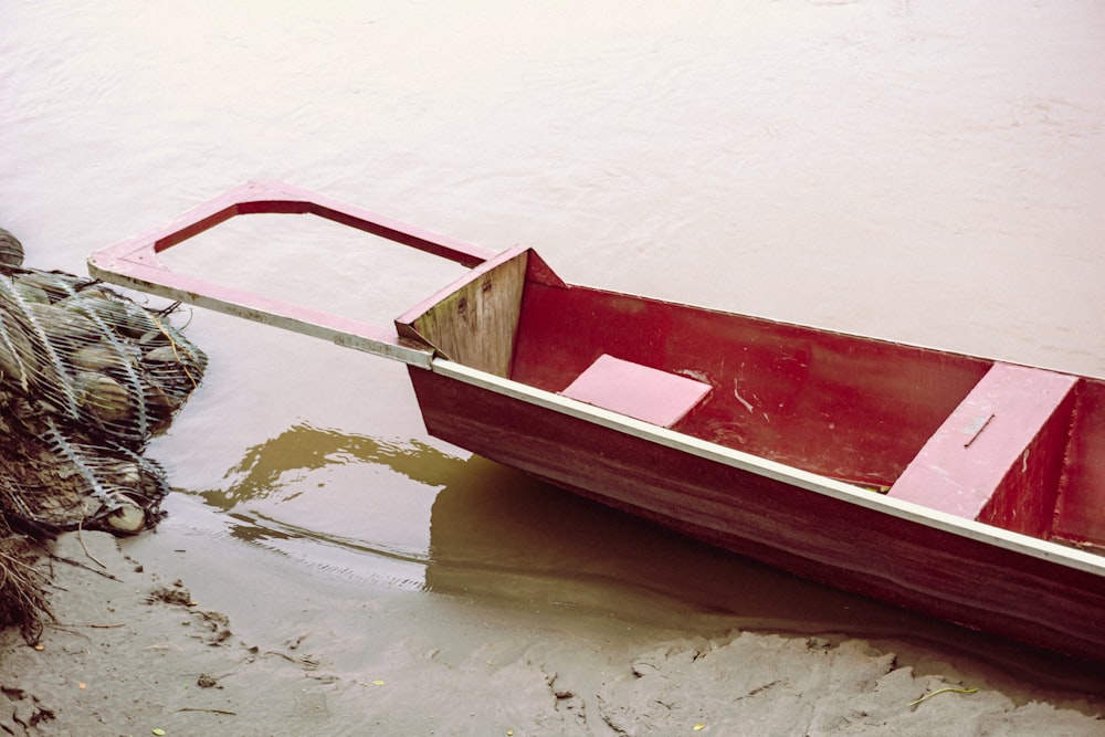 a red boat is tied to a rope in the water