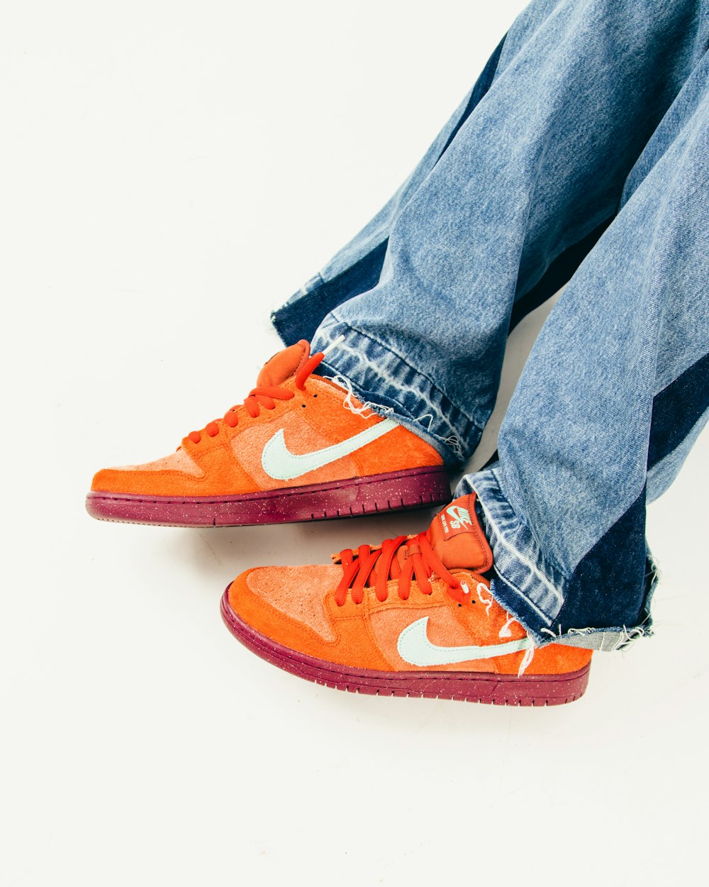 a pair of jeans and a pair of orange sneakers