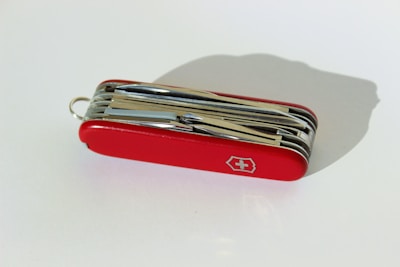 A red multi-functional pocket knife with various foldable tools with a white cross emblem on its side.