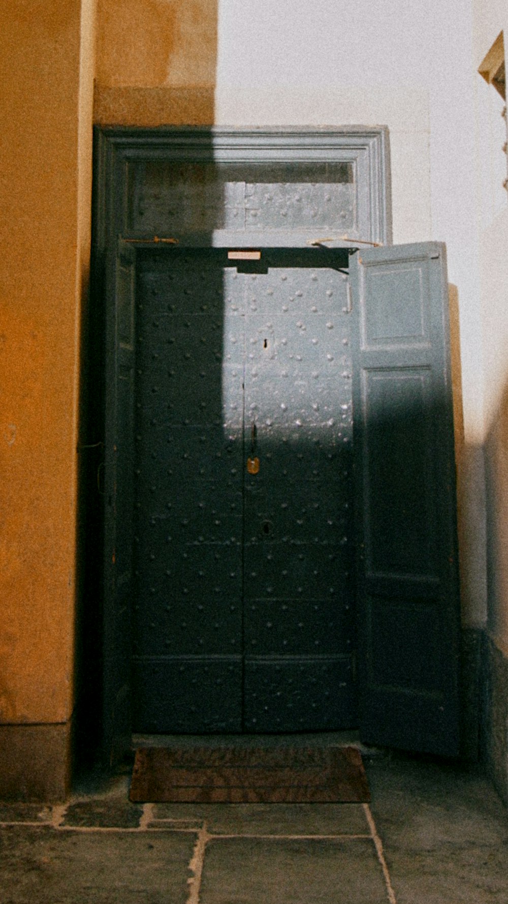 Eine schwarze Tür steht offen an einer gelben Wand