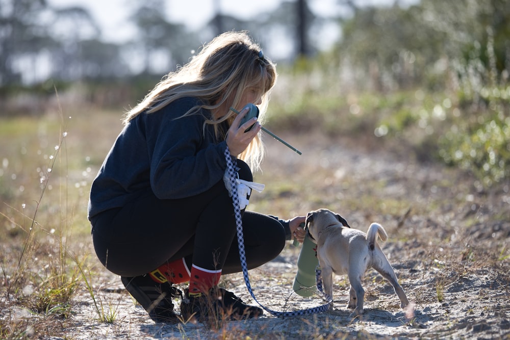 a woman kneeling down with a dog on a leash