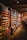 An interior of a vintage-style store is filled with shelves stocked with an assortment of goods, including packaged foods and glass jars. The room features warm wooden shelving and flooring, creating a cozy and nostalgic atmosphere. Soft lighting enhances the rustic charm of the setup.